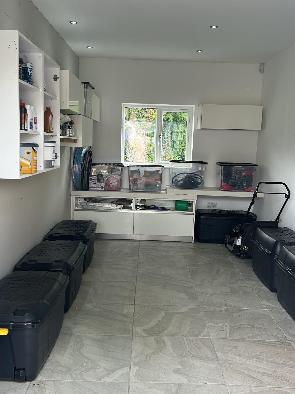 Organised garage with white cabinetry, workbench, and smart floor storage